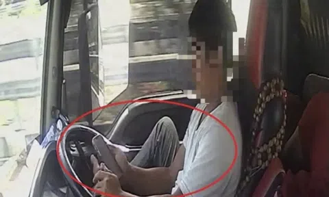 Tài xế dùng chân điều khiển xe đầu kéo chạy trên cao tốc, tay cầm điện thoại lướt TikTok