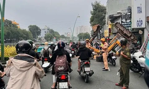 TPHCM: Xe múc đang tháo dỡ nhà bất ngờ lật ngửa giữa đường