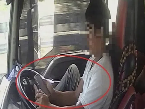 Tài xế dùng chân điều khiển xe đầu kéo chạy trên cao tốc, tay cầm điện thoại lướt TikTok